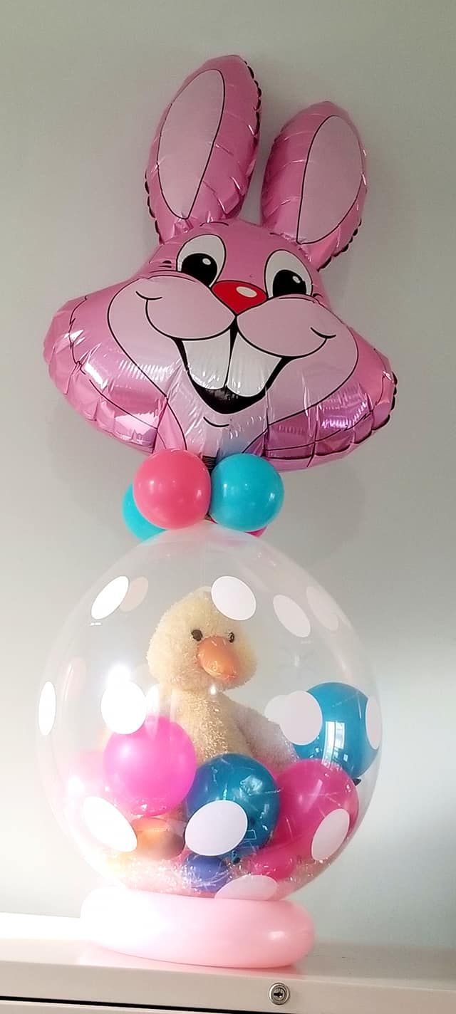 A pink bunny balloon is sitting inside of a balloon filled with balloons.