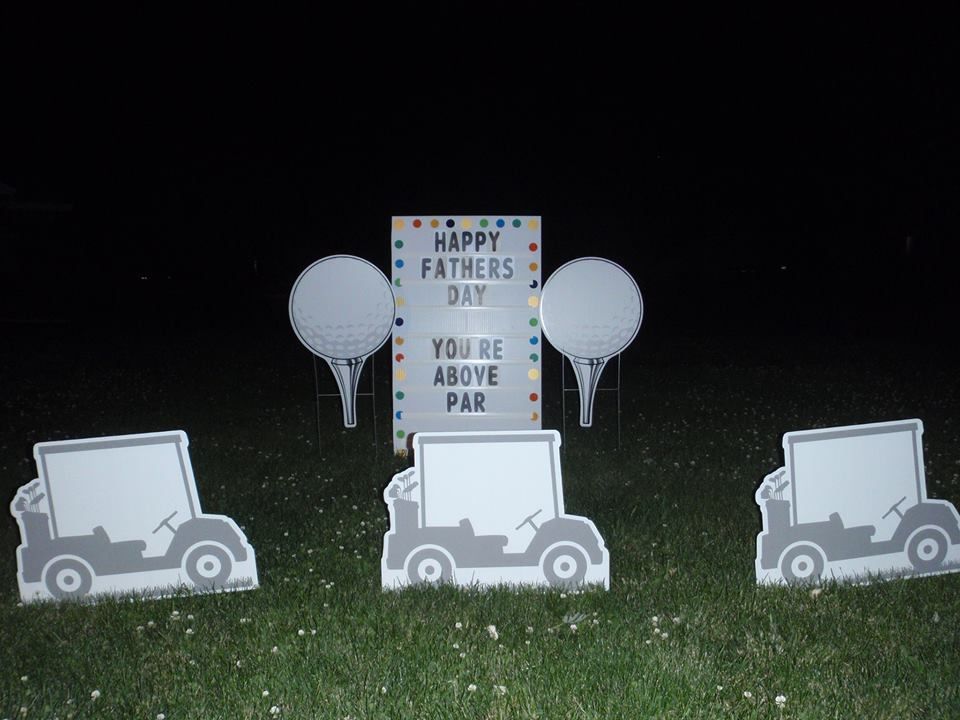 A sign that says happy fathers day on it.  Golf themed yard card.