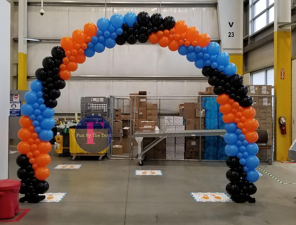 A blue , orange and black balloon arch in an Amazon warehouse.