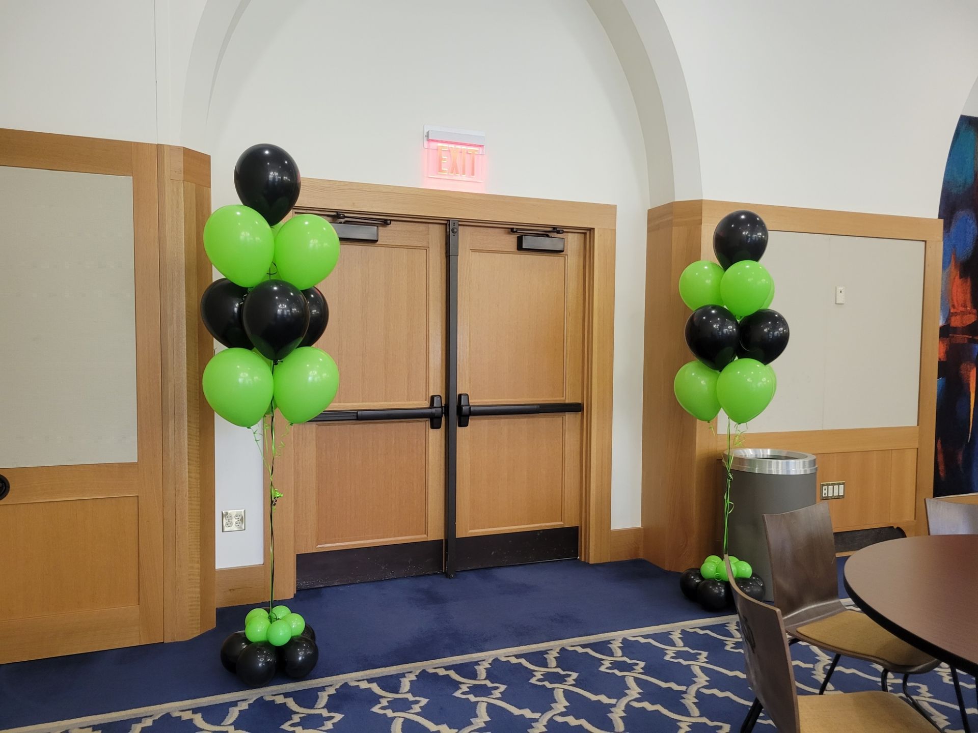 A room with green and black balloons in front of a door for Deloitte