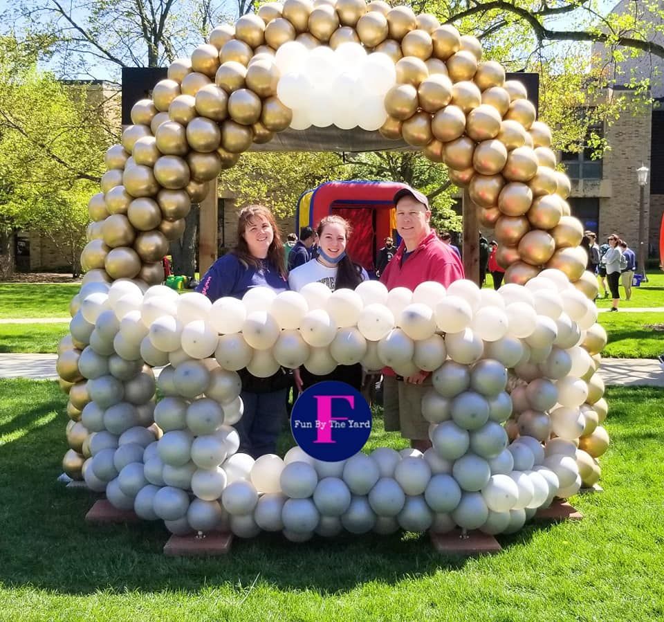 A group of people standing in front of a balloon football helmet