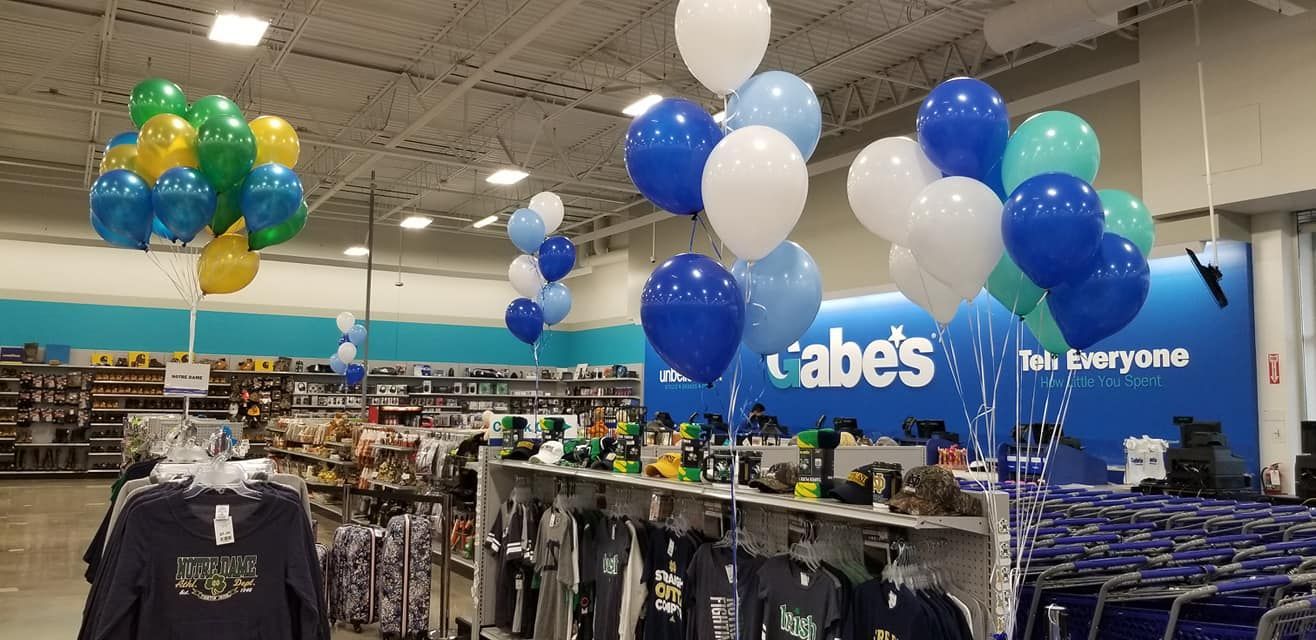 A store with balloons hanging from the ceiling and a sign that says Gabe 's. Grand opening balloon decor.