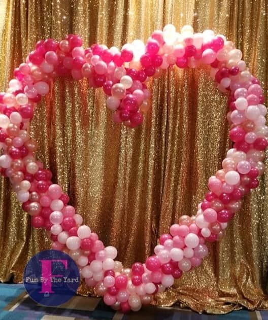 A heart shaped photo op made out of pink and white balloons