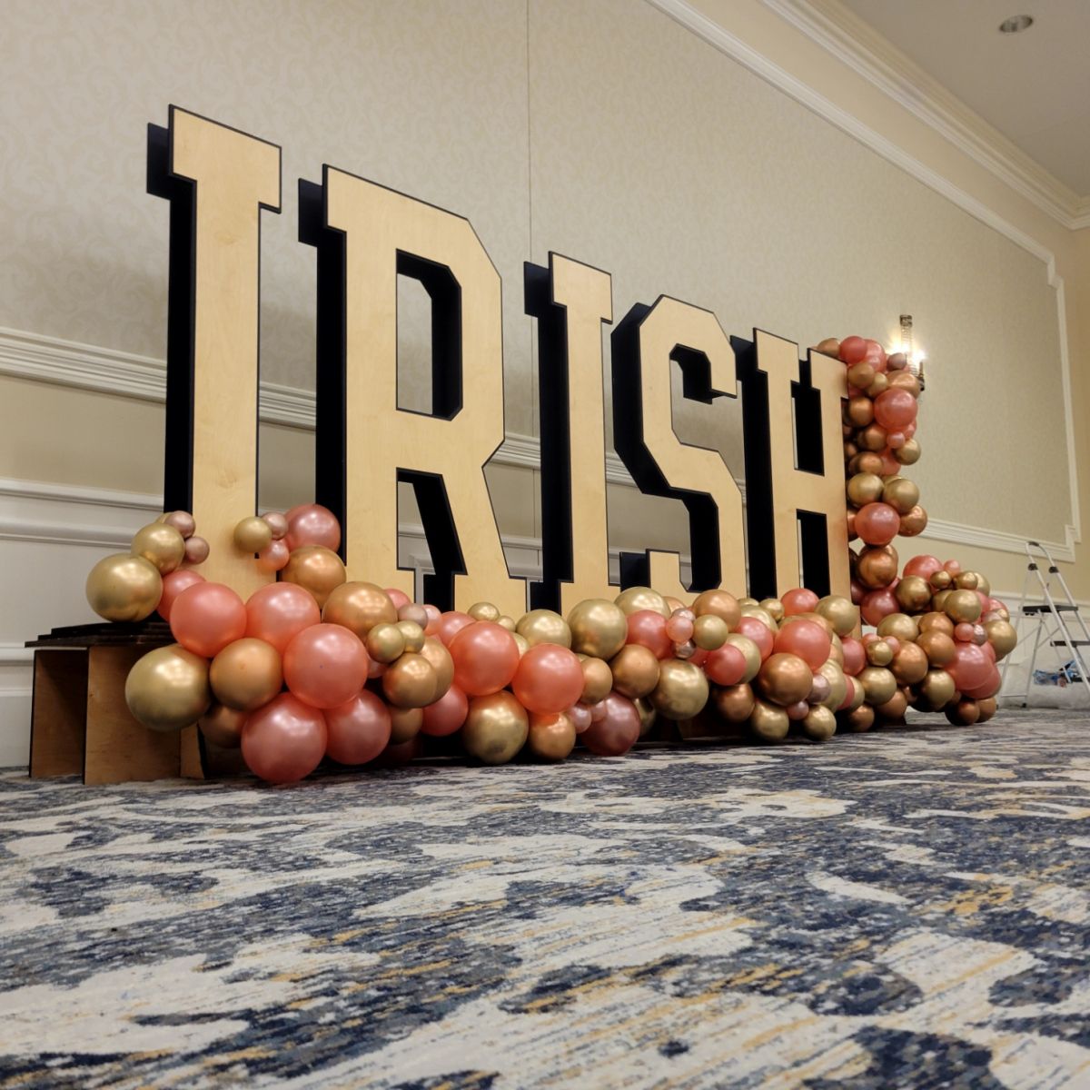 a large sign that says trish is surrounded by balloons on the floor