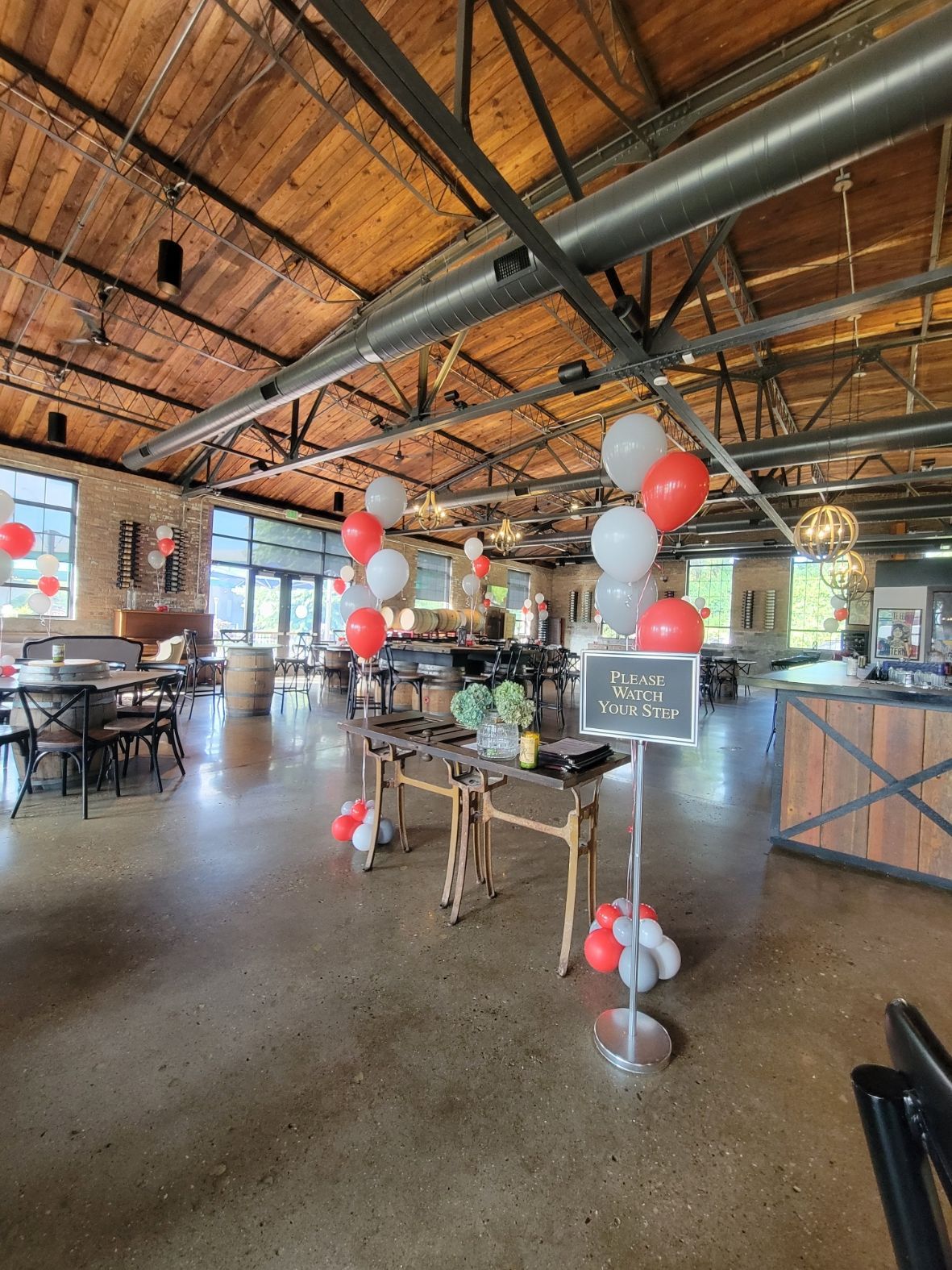 A large room filled with tables and chairs and balloons.