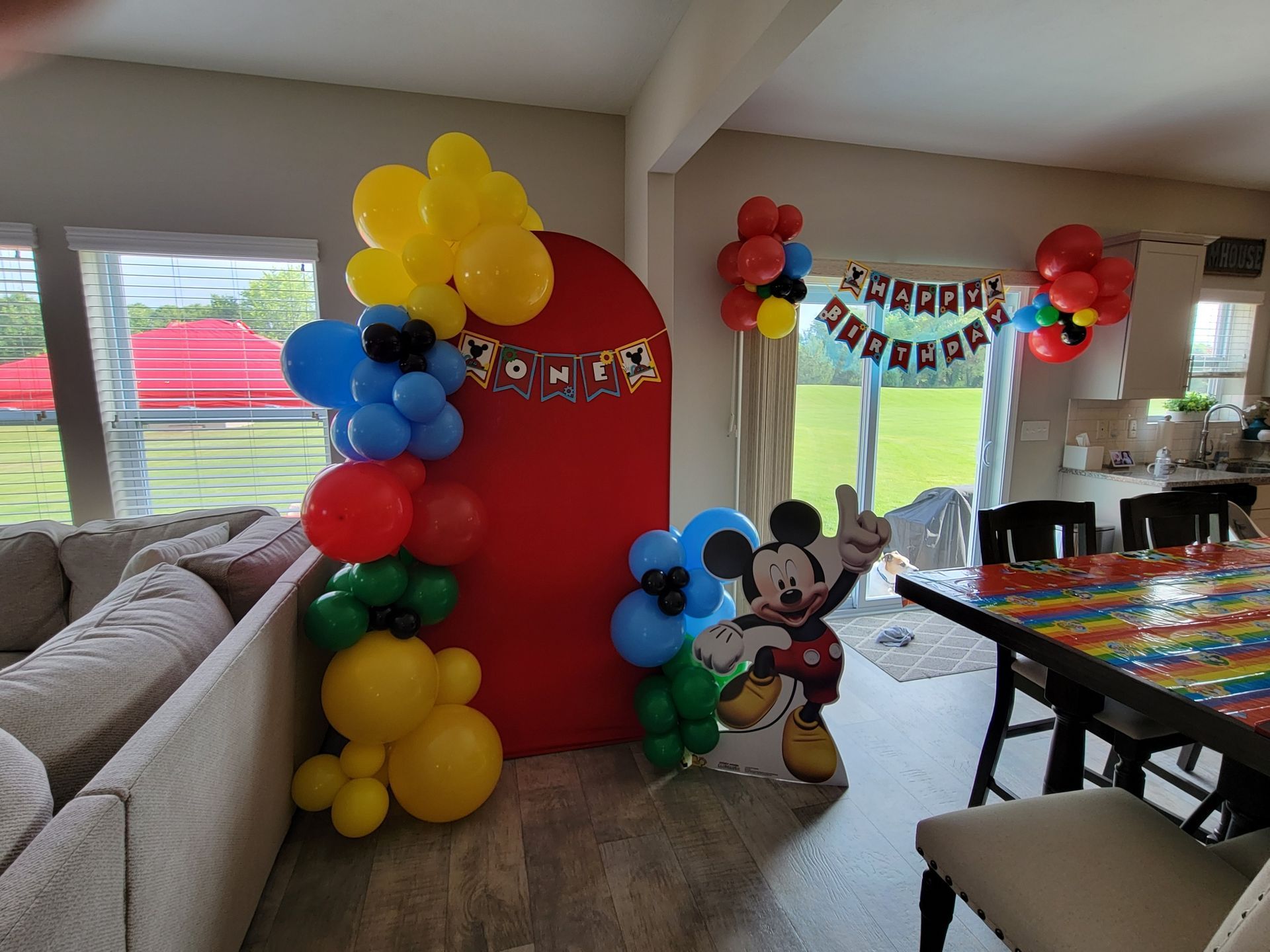 Party decorations with balloons, a red arch, and a Mickey Mouse cutout.