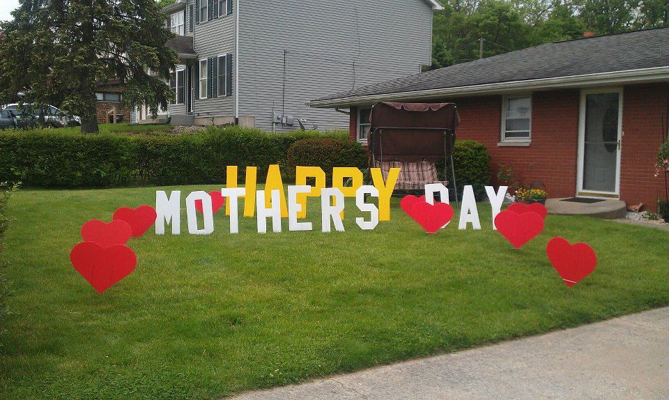 A happy mother 's day sign in front of a brick house