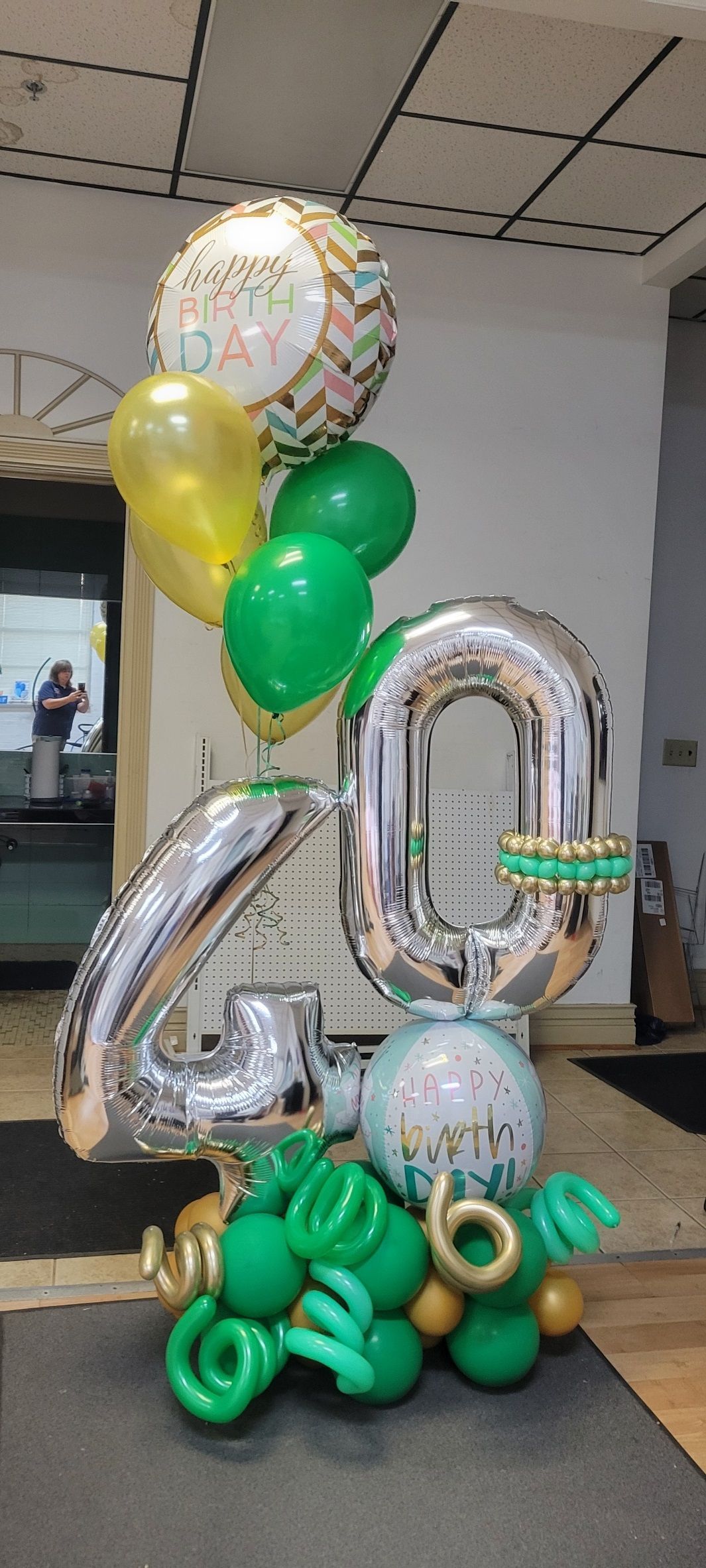 A balloon arrangement for a 40th birthday. Silver numbers, green, gold, and a round
