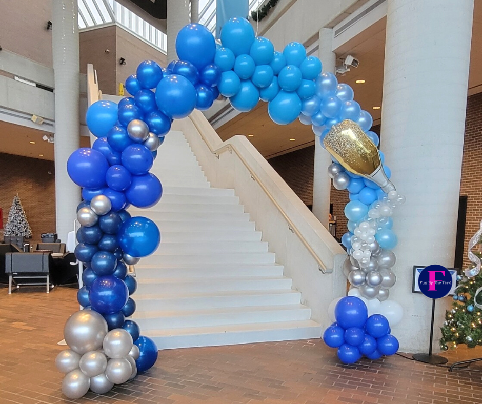 A blue and silver balloon arch in front of stairs
