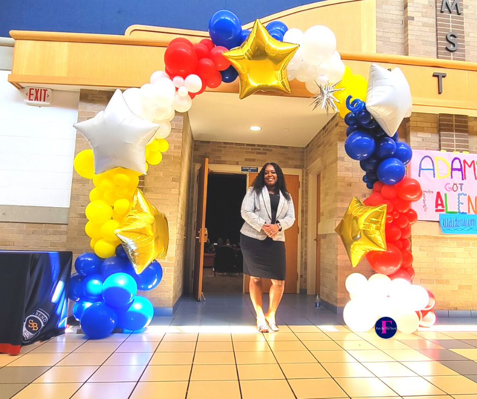 A woman is standing in front of a building decorated with balloons.