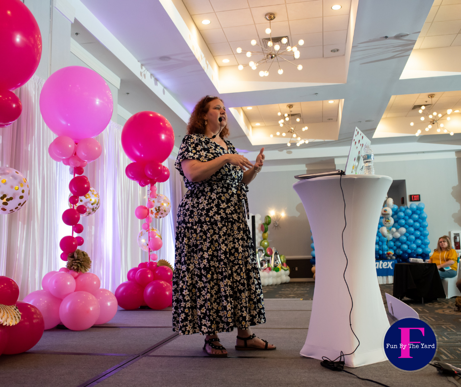 A woman is standing in front of a table with balloons on it. Stage with balloon decor.