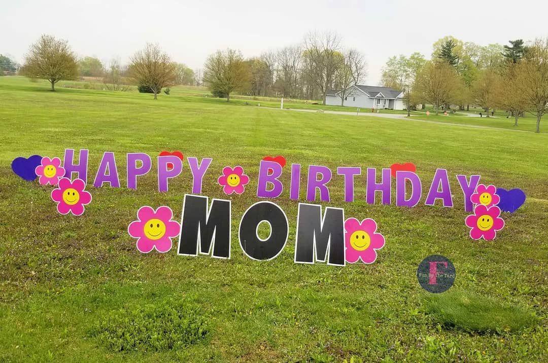 A happy birthday mom sign is in the middle of a grassy field.