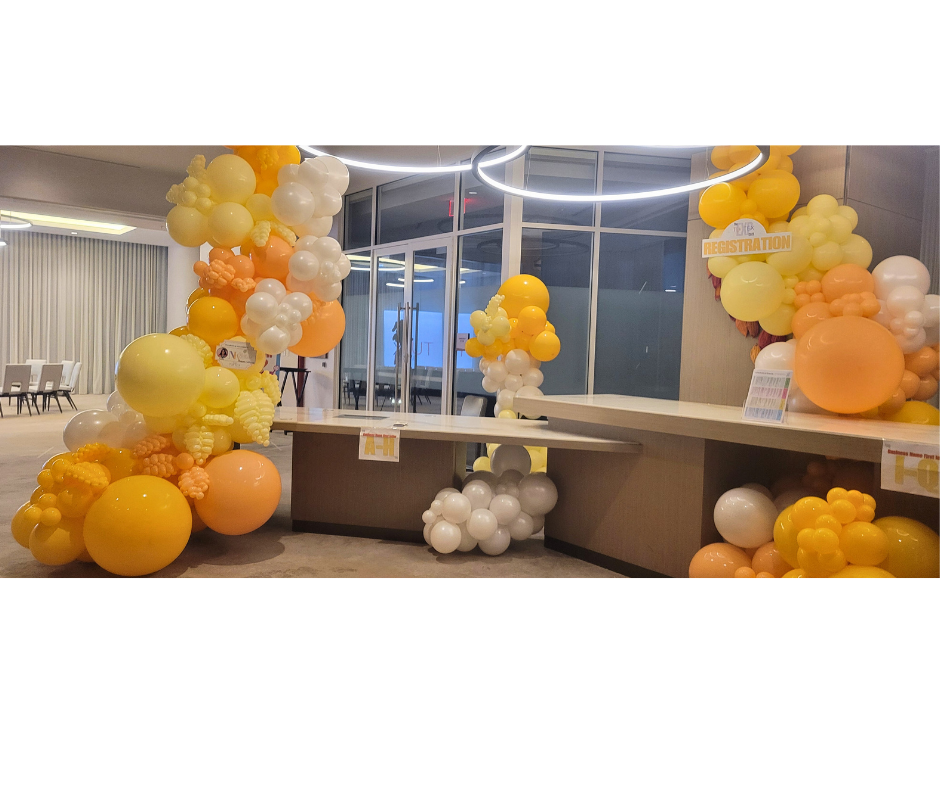 Decorated reception desk with yellow, white, and orange balloons.