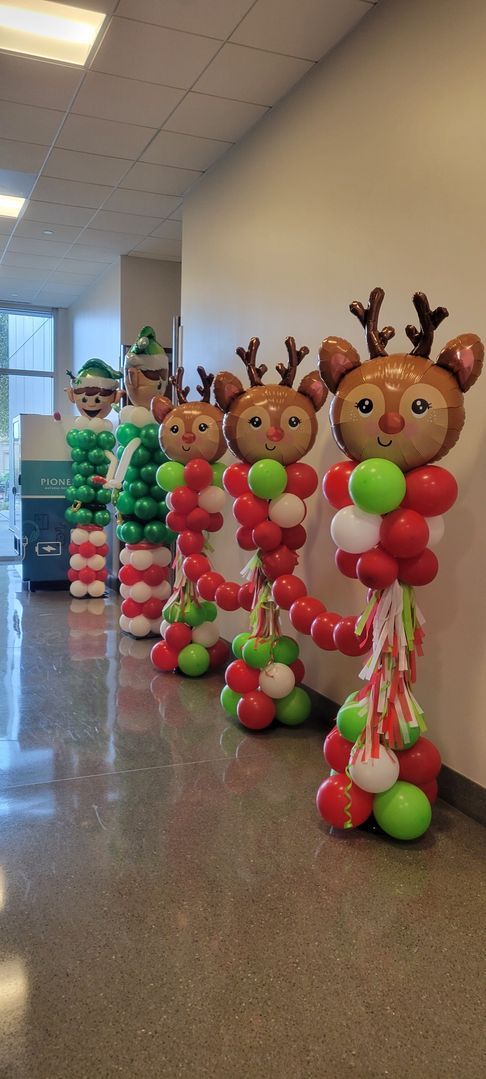 Christmas balloon decorations in a hallway, featuring reindeer and an elf. Red, green, and white balloons.
