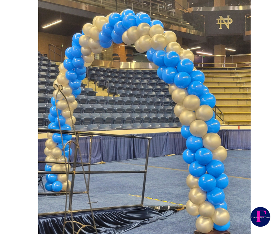 Balloon arch in blue and gold colors, set up indoors over a walkway.