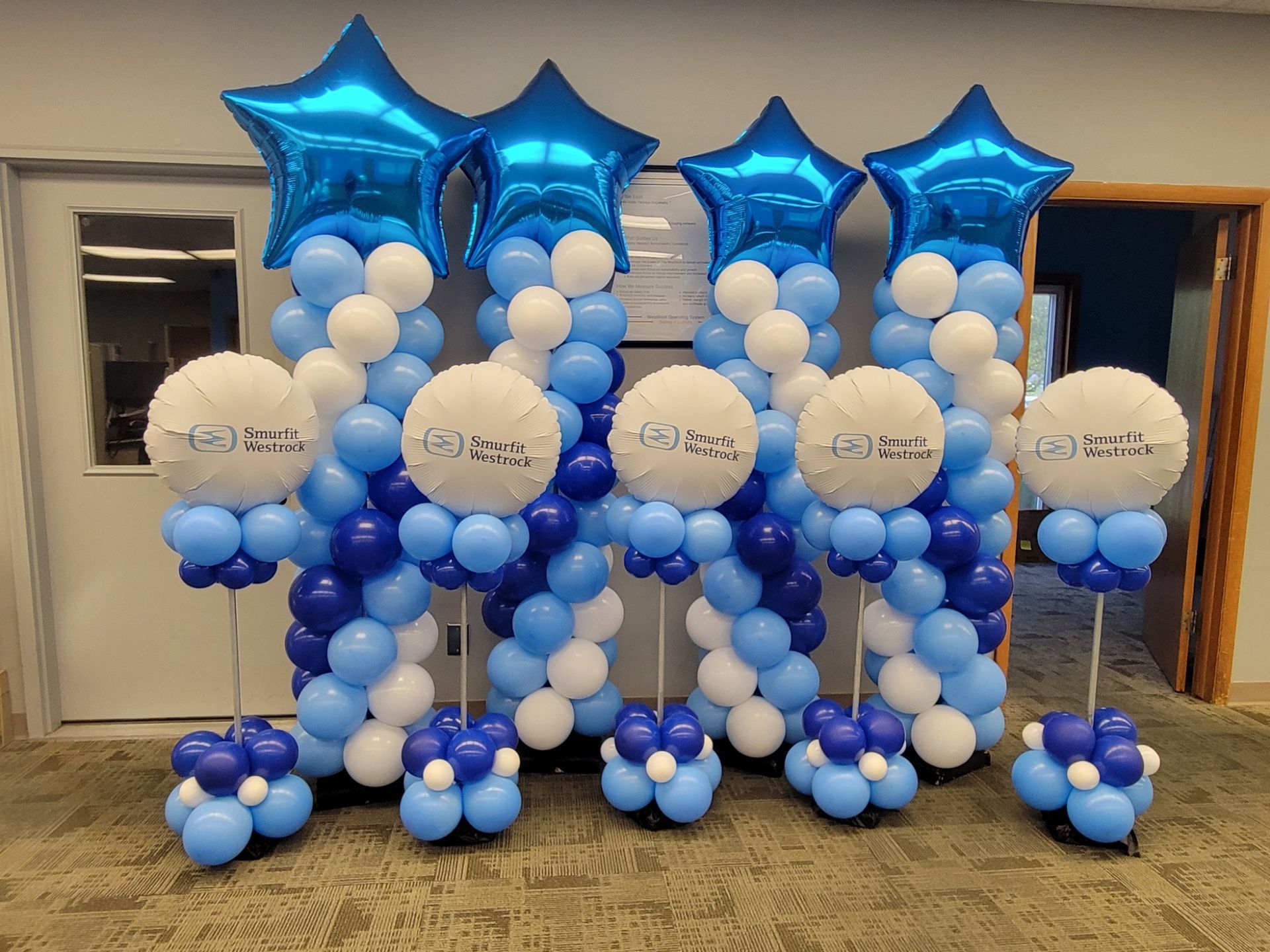 Blue and white balloon decorations with star balloons and logo balloons, indoors.