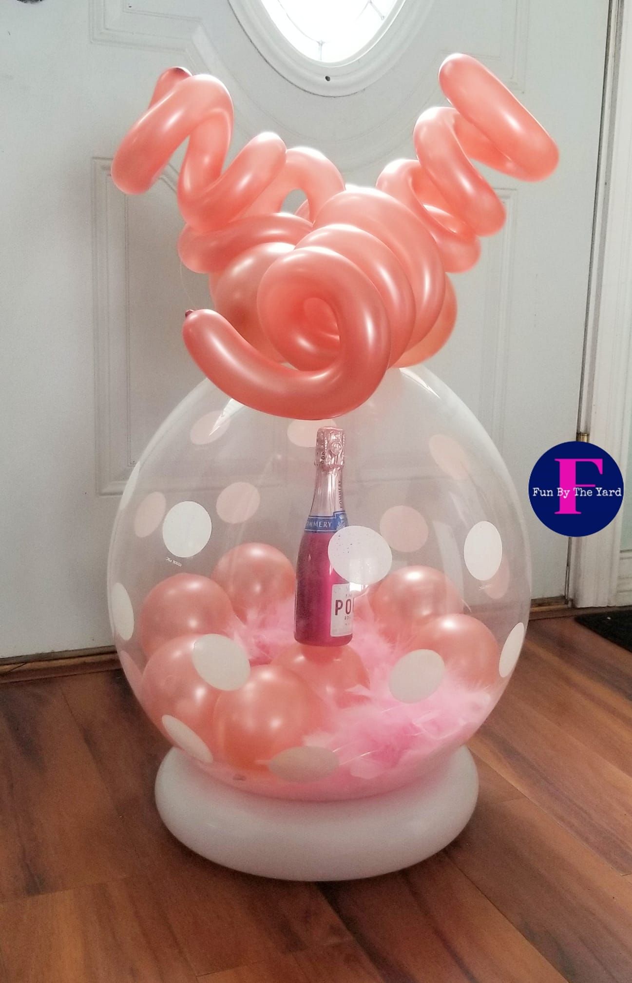 A balloon filled with pink balloons and a bottle of champagne.