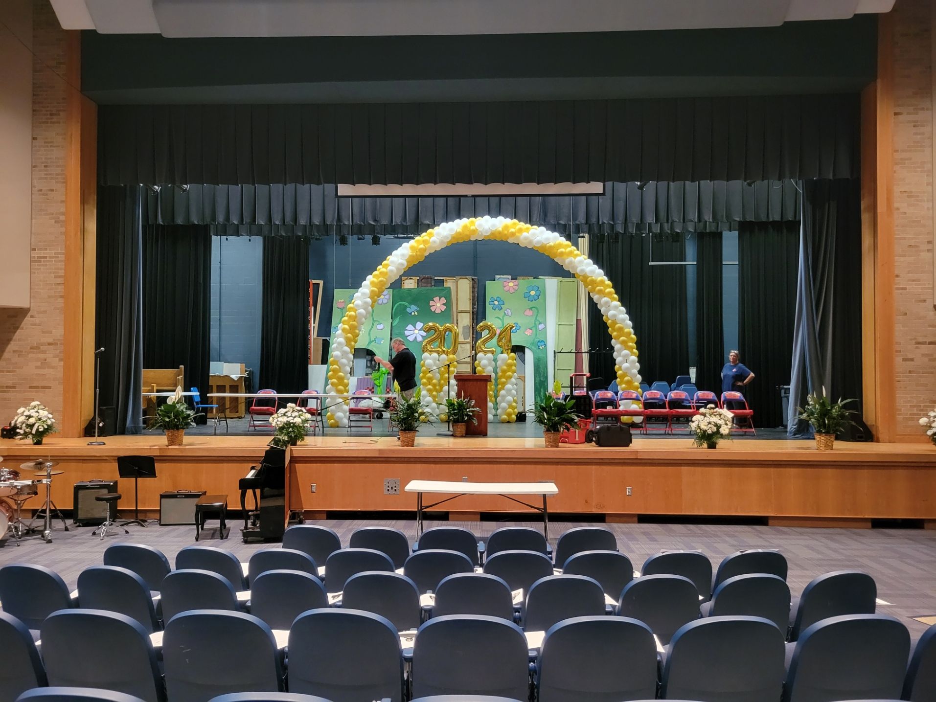 An empty auditorium with a stage decorated with balloons and flowers.