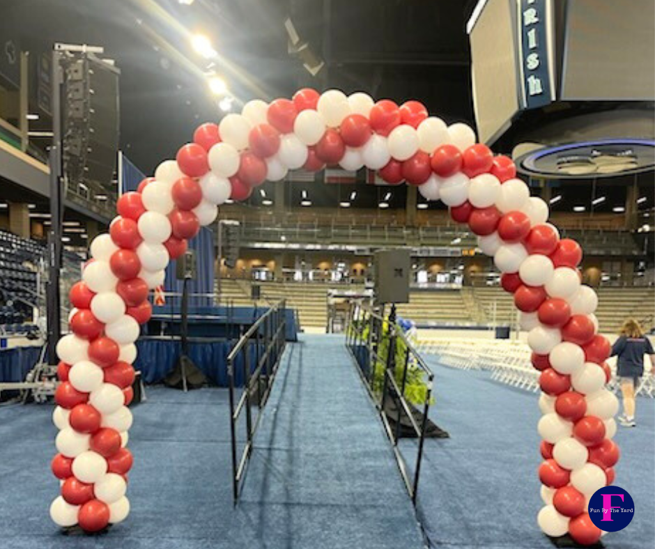 Balloon arch in red and white over a pathway, set up at an event.