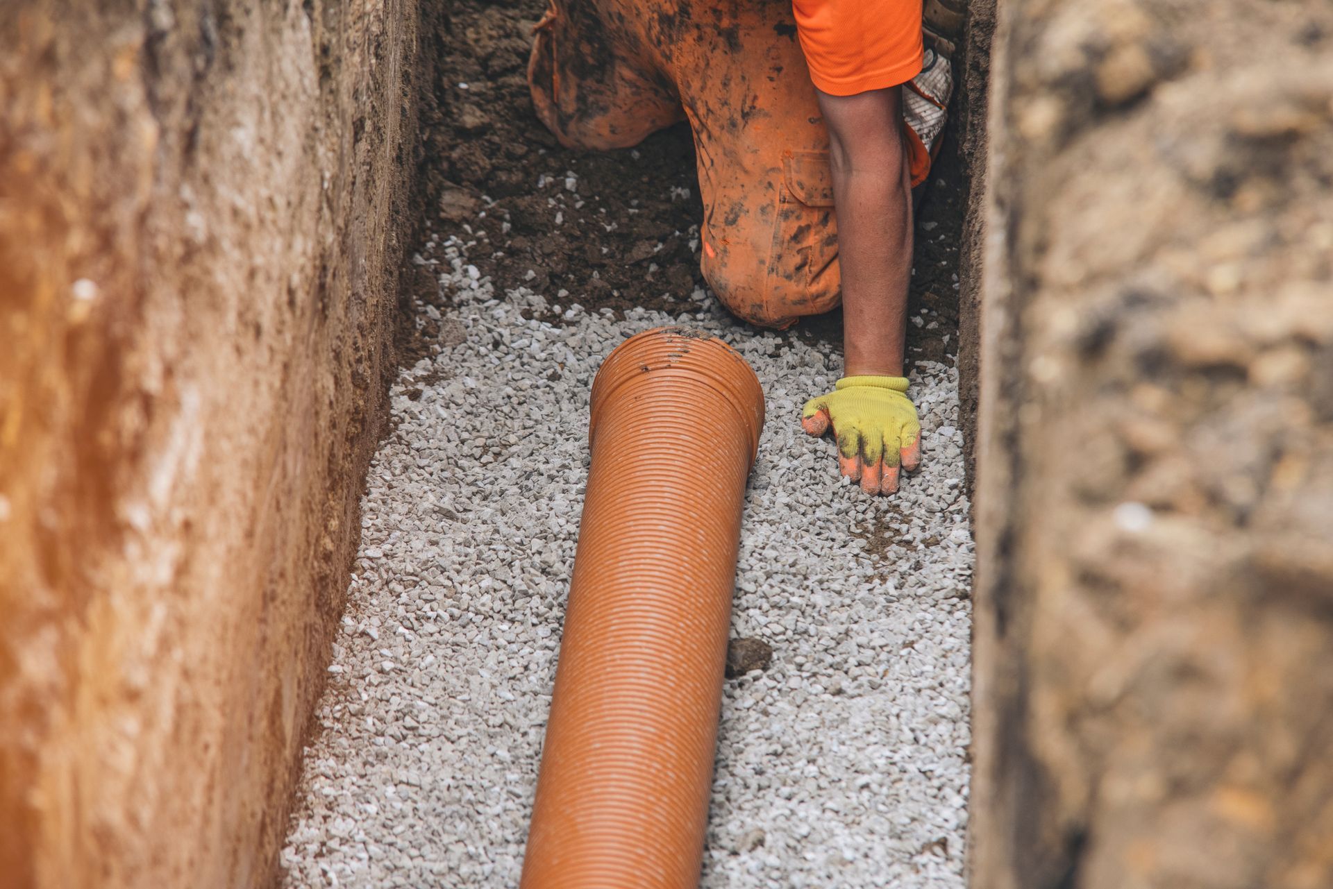 A man is laying a pipe in a trench.