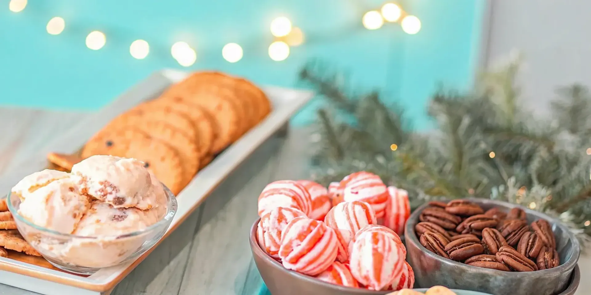 A festive Christmas dessert spread with peppermint and pumpkin ice cream, candied pecans, and holiday cookies on a warm wooden table