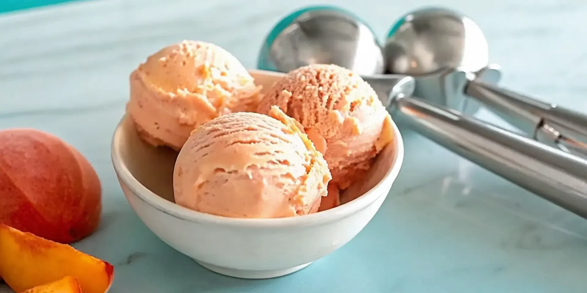 Creamy homemade peach ice cream in a bowl with fresh peach slices.