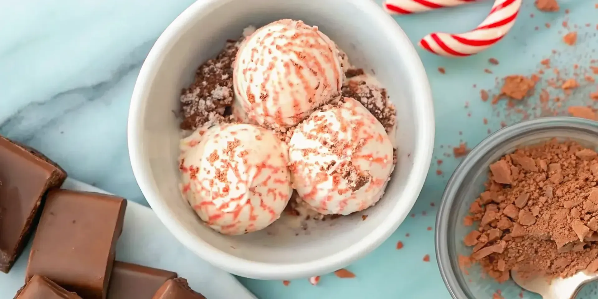 Peppermint bark ice cream in a bowl with chocolate chunks and crushed peppermint candy.