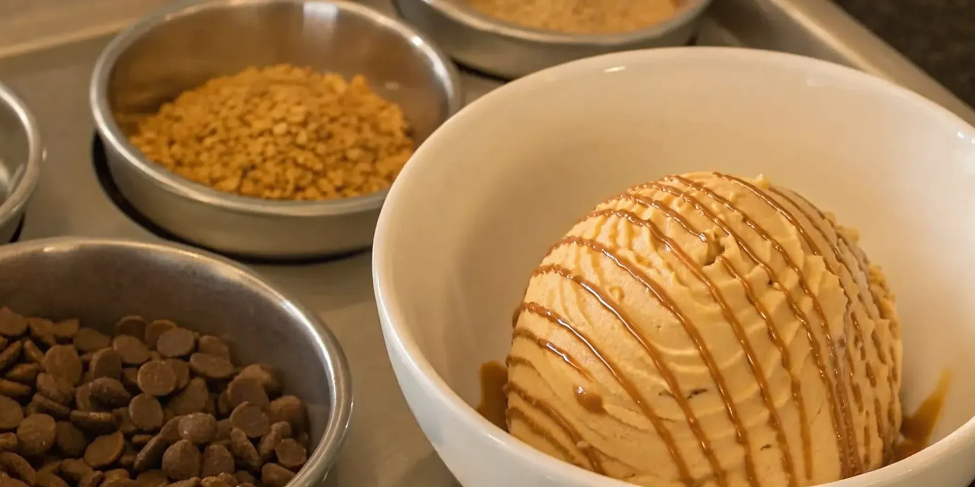 A bowl of toffee ice cream with caramel sauce, chocolate chips, and crunchy toffee bits.