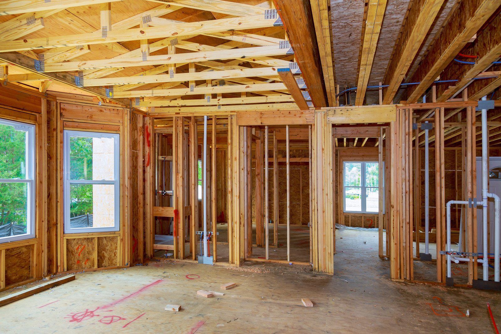 Interior of a home under construction with wooden framing, windows, and open doorways.