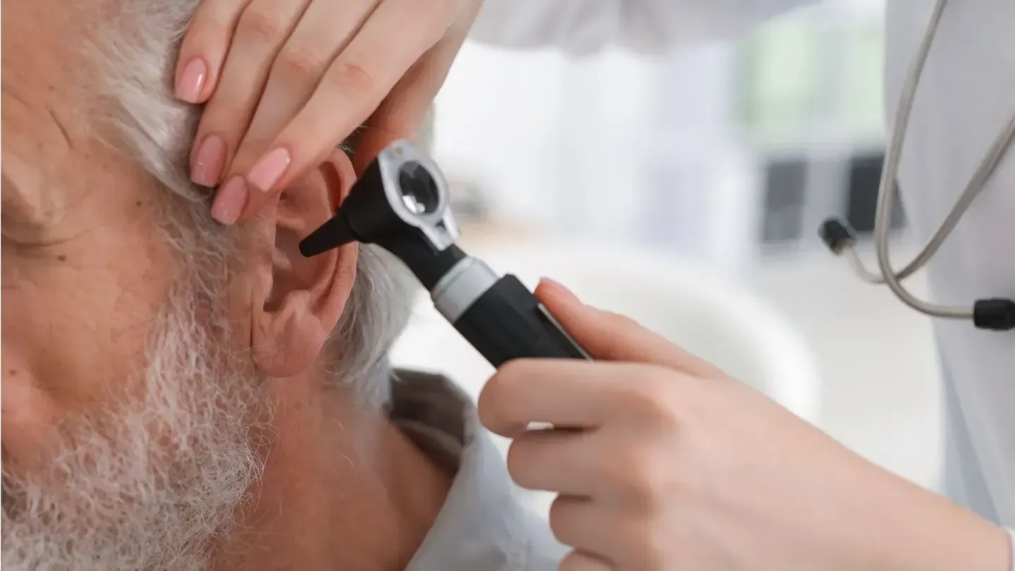 Doctor examining a patient's ear with an otoscope.
