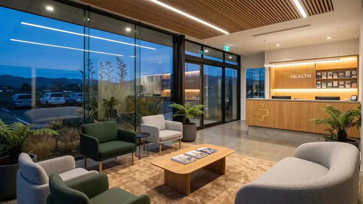Modern lobby lounge with green chairs, wooden table, reception desk, and city view at dusk