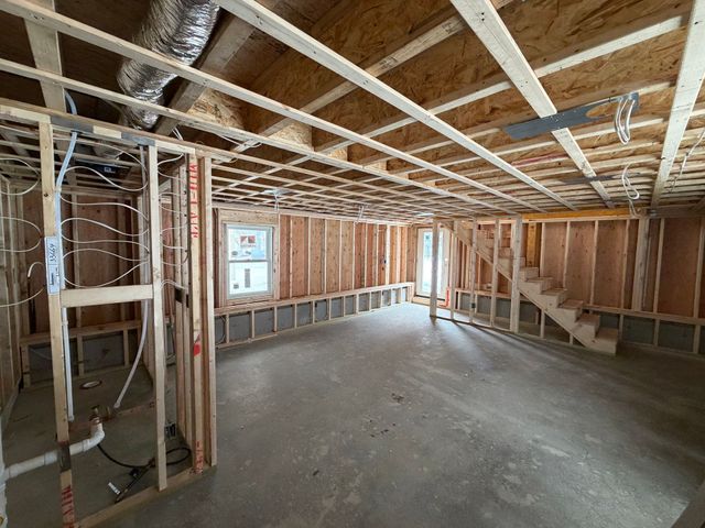 Interior view of a building under construction, showing wooden framing, electrical wiring, and a circuit breaker panel.