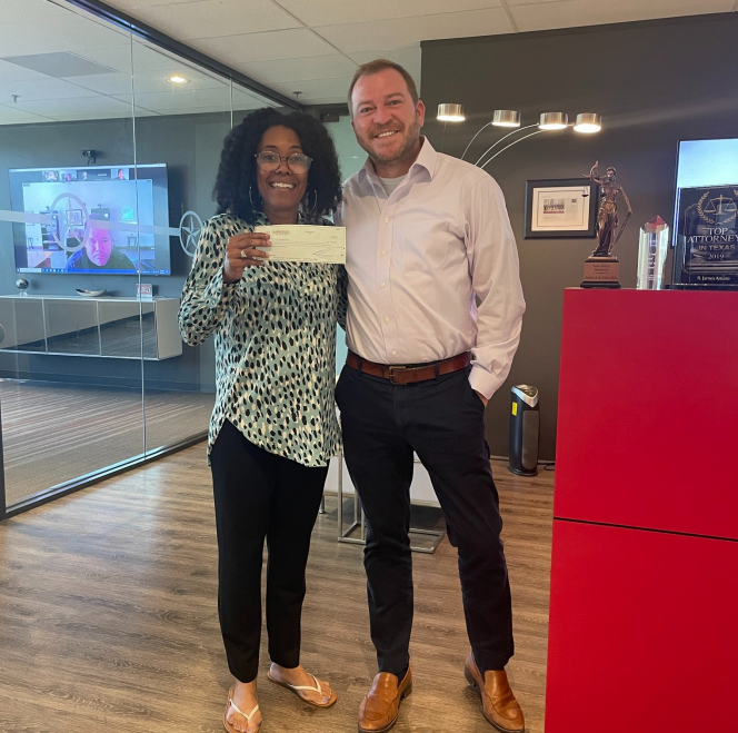A man and a woman standing next to each other holding a check