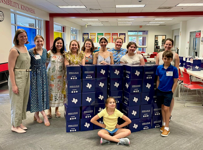 A group of people are posing for a picture in front of a stack of boxes.