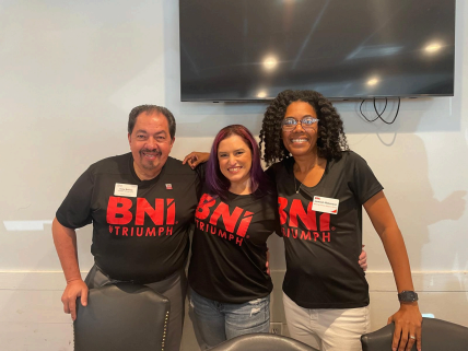 A man and two women wearing bni triumph shirts are posing for a picture.