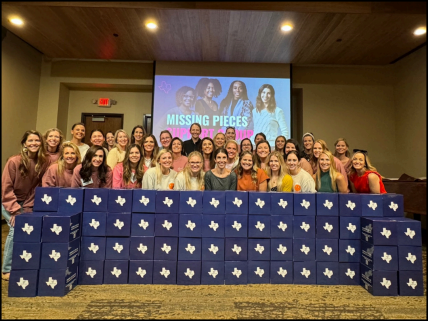A group of people are posing for a picture in front of a projector screen that says missing pieces