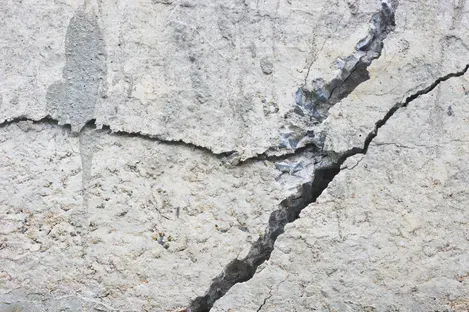 Close-up of a cracked concrete wall with a large diagonal fracture