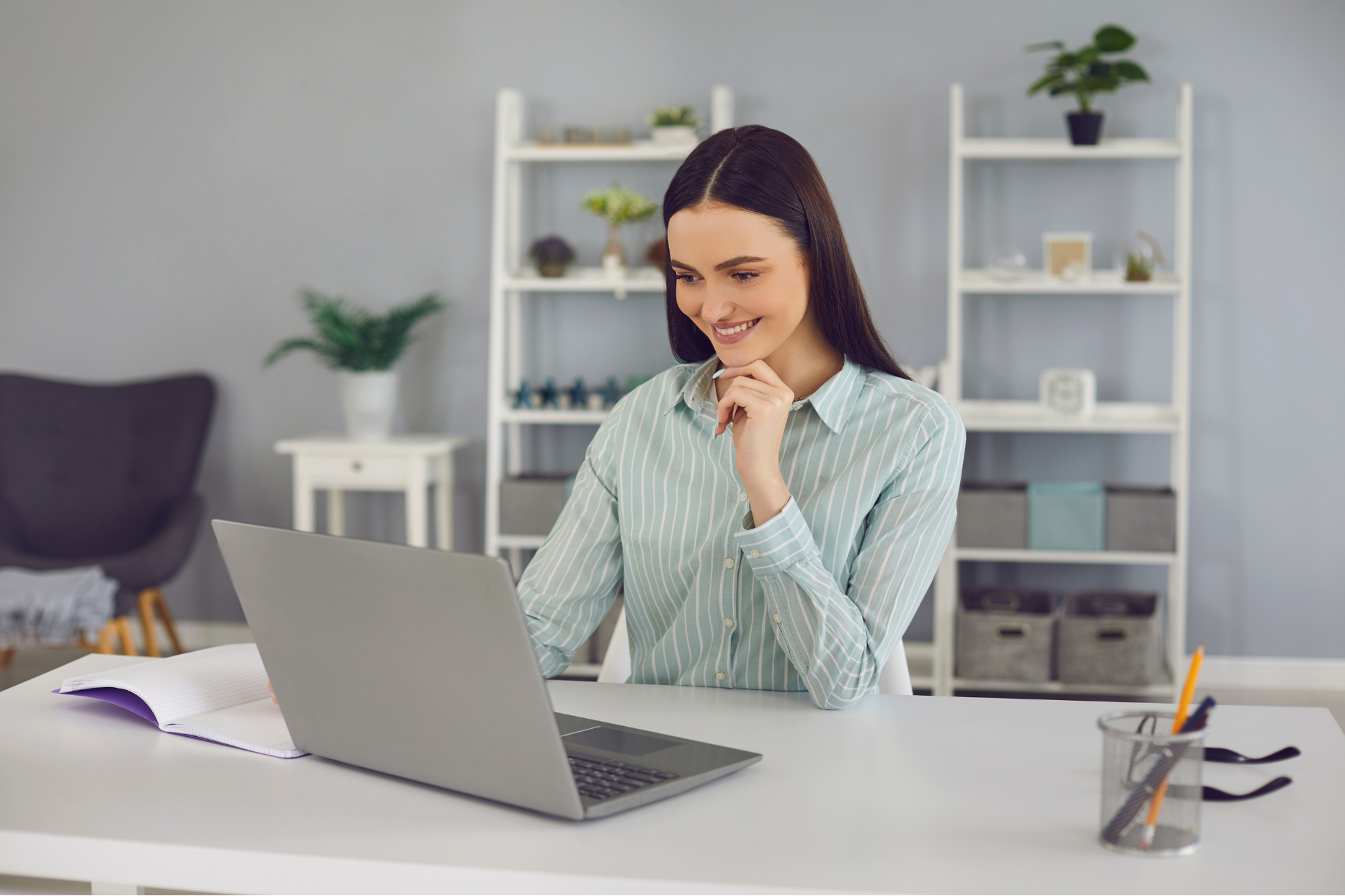 Woman working on a laptop at a desk in a bright home office