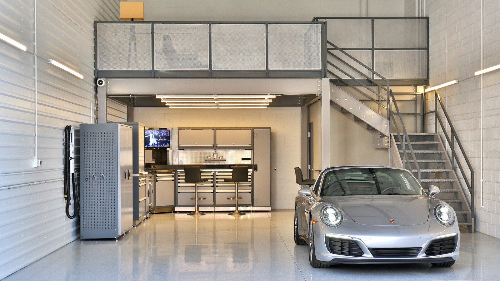 Modern garage interior with a silver sports car, mezzanine loft, and staircase