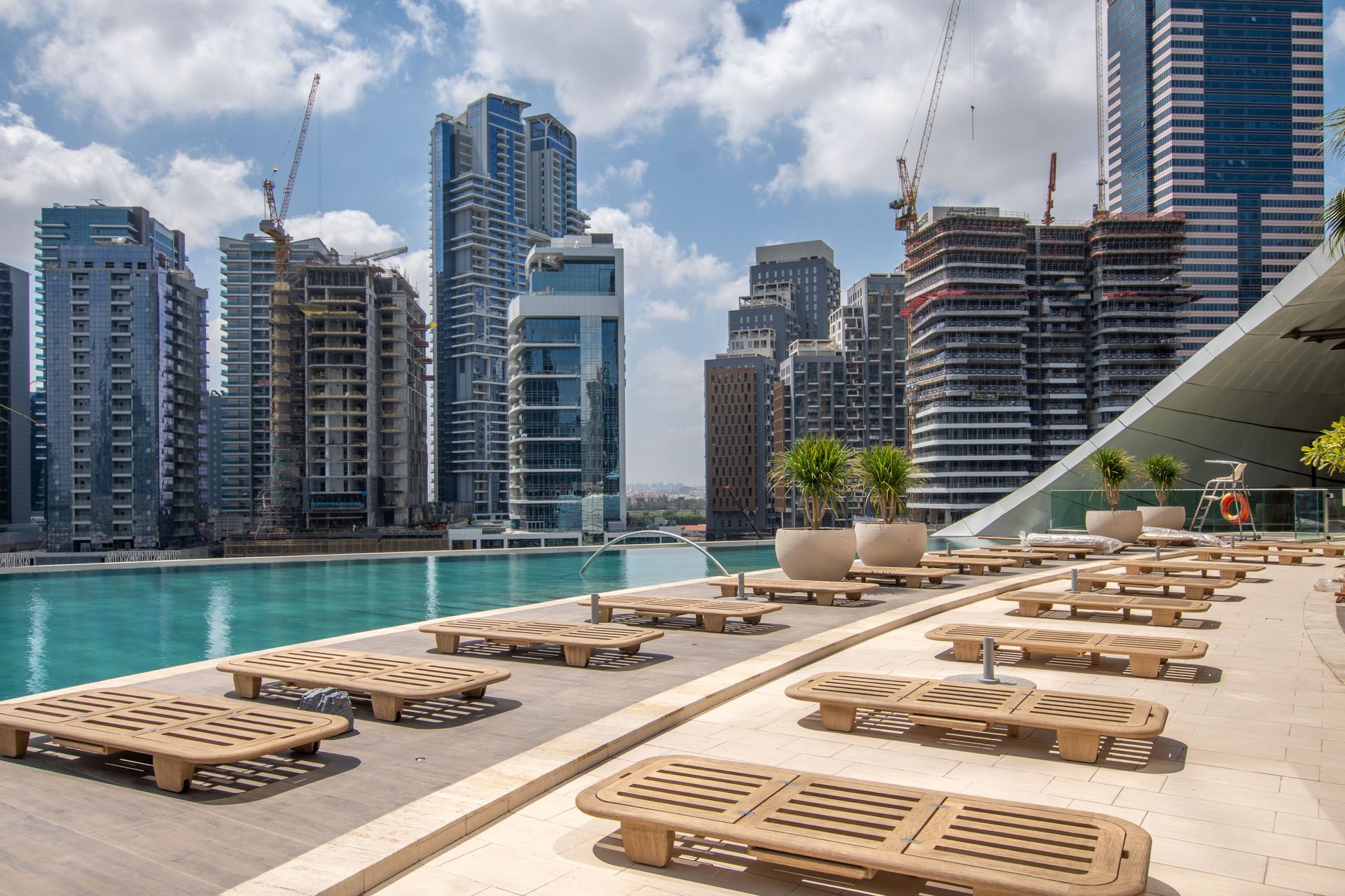 Luxury pool deck with loungers beside turquoise water and high-rise waterfront buildings