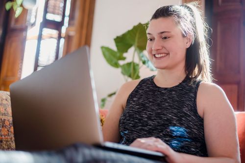Two people embracing at a laptop in a bright kitchen, with a blue mug on the counter.