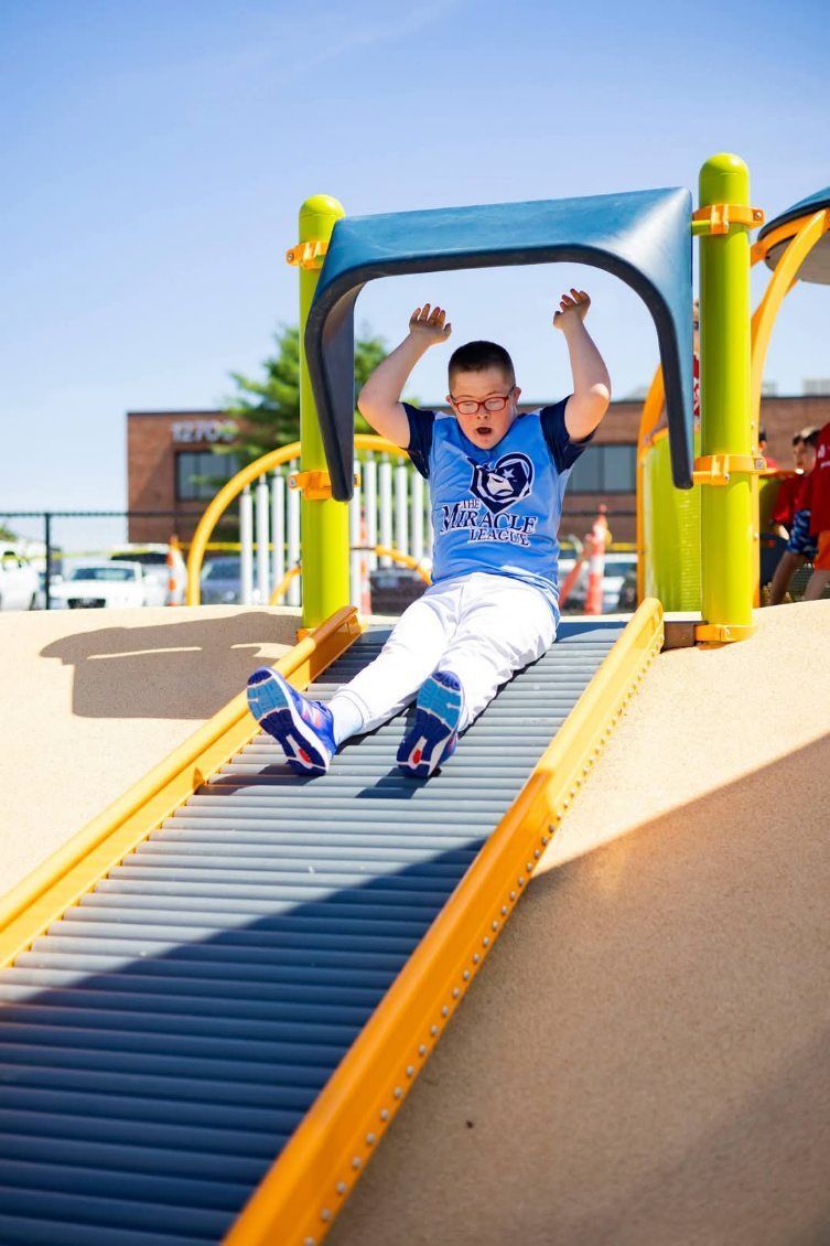 A boy is sliding down a slide at a playground
