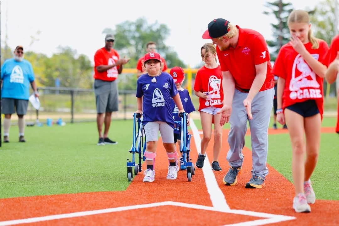 A group of children are walking on a baseball field.