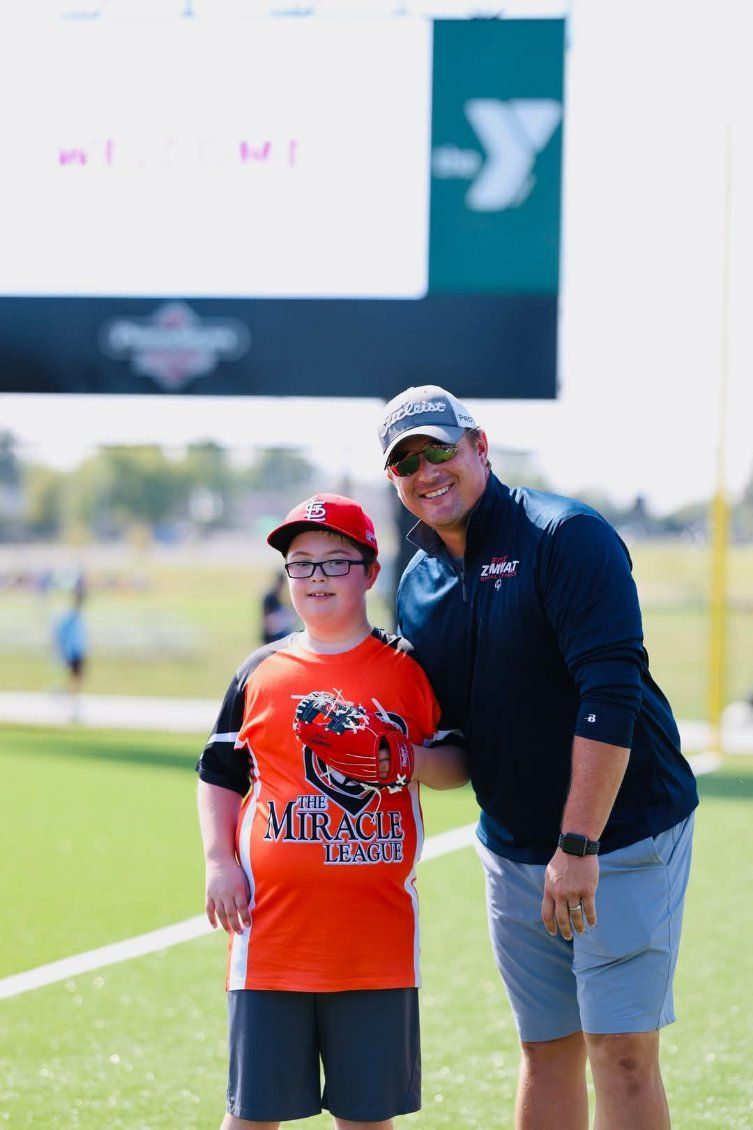 A man and a boy are posing for a picture on a football field.