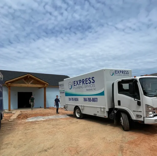 Express delivery truck parked in front of a building under construction; two men walk by.