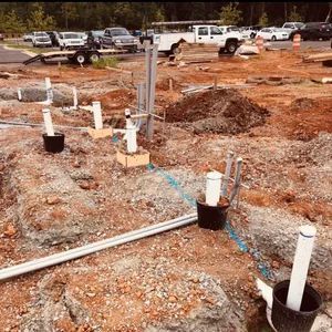 Construction site with exposed plumbing and foundation work in progress.