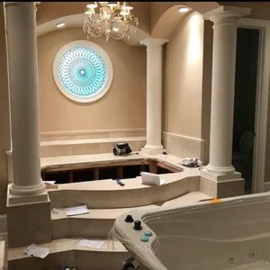Bathroom renovation: tub removed, columns, round window with blue design, chandelier.
