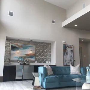 Living room with blue couch, artwork, bar area, and high ceilings.