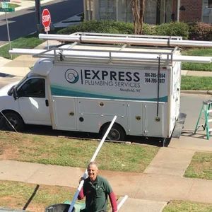 Express Plumbing Services van parked by a house, with a worker holding a long pole in the foreground.