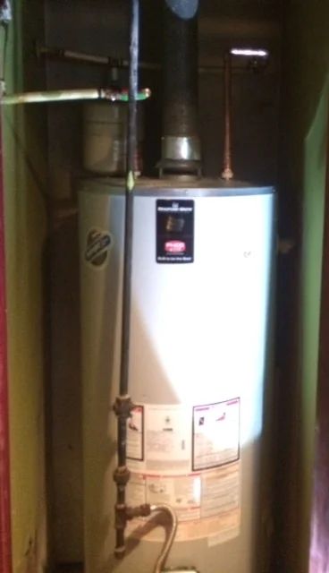 Water heater in a utility closet with vent pipe and copper plumbing.